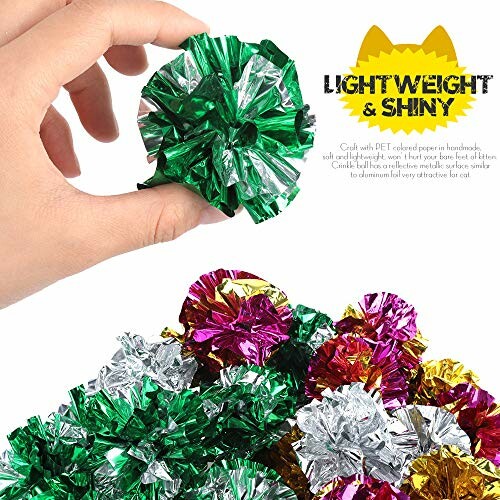 Hand holding a lightweight shiny crinkle ball toy for cats with colorful balls below.