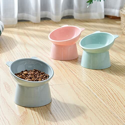 Three elevated cat bowls, two empty and one with food, on wooden floor.